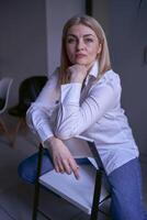 Porträt von ein blond Frau im Jeans und ein Weiß Hemd im das Büro foto