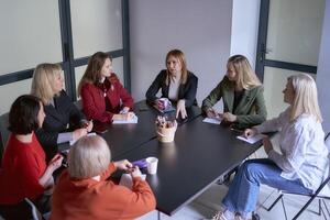 ein Mannschaft von Sieben Frauen ist halten ein Treffen im das Büro foto