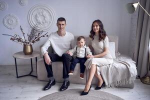 schön Familie Sitzung auf Sofa mit ihr wenig Junge im minimalistisch Studio foto