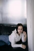 jung Teenager Mädchen Kampf Gehirn Krebs beim Foto schießen im Studio, Metall Wand, Betrachtung, schwarz Sofa