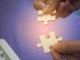Hände von ein Frau halten und verbinden Puzzle Puzzle mit ein Blau Hintergrund und Sonnenlicht Wirkung. Raum zum Text. Konzept von Geschäft und Partner foto