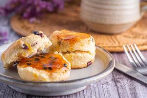 Nahansicht von traditionell britisch Scones auf ein Teller mit ein Tasse von Tee mit Blume verschwommen Hintergrund foto