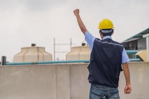 Ingenieur steht auf dem Dach des Produktionsgebäudes zeigt Engagement und Erfolg foto