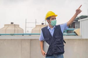 Ingenieur steht auf dem Dach des Produktionsgebäudes zeigt Engagement und Erfolg foto