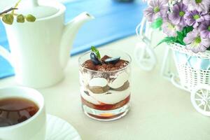 Tasse von Tee und Vase von Blumen auf Tabelle foto