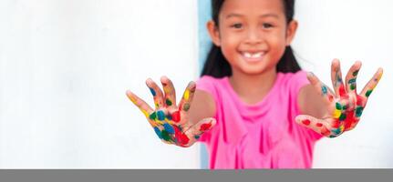süß wenig Mädchen mit bunt gemalt Hände auf Mauer Hintergrund foto