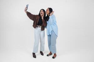 weiblich freunde Lachen und nehmen ein Spaß Selfie isoliert durch Weiß Hintergrund foto