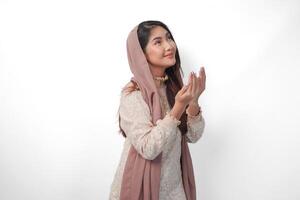 religiös asiatisch Muslim Frau tragen Schleier Kopftuch mit Hände im beten Geste zu Gott, Stehen Über isoliert Weiß Hintergrund. Ramadan und eid al fitr Konzept foto