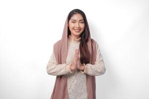 schön asiatisch Muslim Frau tragen Kopftuch Schleier Hijab lächelnd zu das Kamera und gestikulieren traditionell Gruß isoliert Über Weiß Hintergrund foto