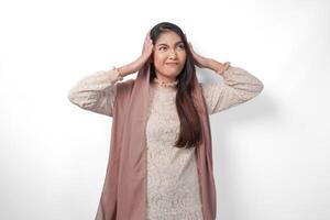 ein asiatisch Muslim Frau erziehen beide Hände zu halt ihr Kopf Gefühl betont und überwältigt, Weinen und schreiend verzweifelt, isoliert Weiß Hintergrund foto