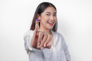 jung asiatisch Frau stolz zeigen wenig Finger eingetaucht im lila Tinte nach Wählen zum Präsident und Parlament Wahl, ausdrücken Aufregung und Glück foto