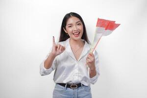 Porträt von glücklich asiatisch Frau stolz zeigen wenig Finger eingetaucht im lila Tinte nach Wählen zum Präsident und Parlament Wahl, links Hand halten Indonesien Mini Flaggen. Unabhängigkeit Tag Konzept. foto