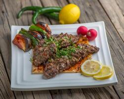 Fleisch Halabi Kebab serviert im ein Gericht Seite Aussicht auf hölzern Tabelle Hintergrund foto