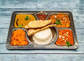 Norden indisch Vegetarier Mahlzeit Thali mit Curry, Reis, Chapati und Gemüse serviert im Gericht isoliert auf hölzern Tabelle oben Aussicht von indisch würzig Essen foto