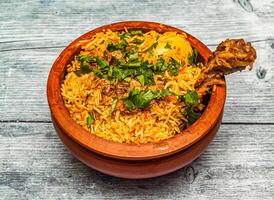 Hähnchen hyderabadi Biryani serviert im Tontopf isoliert auf hölzern Tabelle oben Aussicht von indisch würzig Essen foto