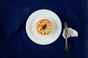 Erdnuss Butter Krapfen mit Messer serviert im Teller isoliert auf Blau Hintergrund oben Aussicht von gebacken Frühstück Essen foto