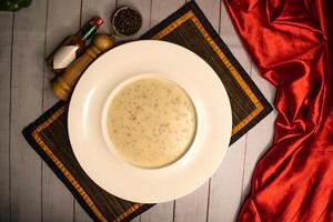 Pilz Sahne Suppe mit schwarz Pfeffer und Knoblauch Chili Soße serviert im Schüssel isoliert auf Serviette oben Aussicht auf hölzern Tabelle Italienisch Essen foto