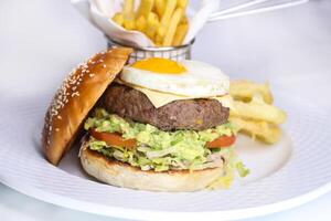 Rindfleisch Burger mit sonnig Seite oben Ei und Französisch Fritten Eimer serviert im Gericht isoliert auf Tabelle Seite Aussicht von Arabisch Essen foto