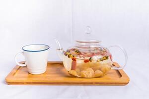 lange, Wolfsbeere und klein Gelb Chrysantheme Tee serviert im Tasse und Teekanne isoliert auf hölzern Tafel Seite Aussicht von Frühstück trinken foto