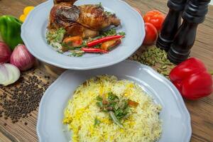 Hälfte gegrillt Hähnchen mit pulao Reis Biryani, schwarz Pfeffer, Glocke Pfeffer, Tomate und Zwiebel serviert im Gericht isoliert auf Tabelle Seite Aussicht von Arabisch Essen foto