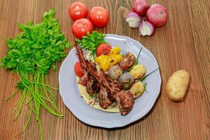 gegrillt Lamm Koteletts mit Pita-Brot brot, Kartoffel, Tomate, Zwiebel und Koriander serviert im Gericht isoliert auf Tabelle oben Aussicht von Arabisch Essen foto