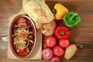 Moussaka mit Kartoffel. Tomate, Glocke Pfeffer, Zwiebel und Pita-Brot Brot serviert im hölzern Tafel isoliert auf Tabelle oben Aussicht von Arabisch Essen foto