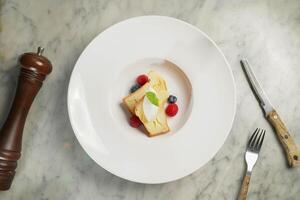 baba au Rum mit Himbeere, Blaubeere, Sahne und Brot serviert im Gericht isoliert auf Marmor Hintergrund oben Aussicht auf Hong kong Essen foto