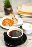 Americano Kaffee serviert im Tasse mit Croissant, Puff Gebäck, Brot und Messer isoliert auf Serviette Seite Aussicht Cafe Frühstück foto