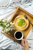 Zitrone Pistazie Krapfen mit Tasse von Kaffee, Gabel und Blumen serviert im Teller isoliert auf hölzern Tablett oben Aussicht von gebacken Frühstück Essen foto