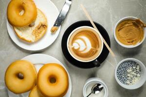 heiß Butterscotch Latté Kunst Kaffee serviert im Tasse mit einfach Donuts, Zucker und Messer isoliert auf Serviette oben Aussicht Cafe Frühstück foto