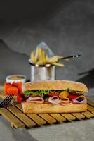 Ciabatta geräuchert Schinken Sandwich isoliert auf hölzern mit Mayonnaise tauchen und Französisch Fritten Eimer Tafel Seite Aussicht von Italienisch schnell Essen auf grau Hintergrund foto