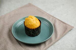 Vanille Muffin Tasse Kuchen serviert im Teller isoliert auf Serviette Seite Aussicht von Cafe gebacken Essen auf Hintergrund foto