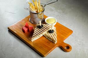 gegrillt Hähnchen Sandwich mit Fritten Eimer serviert im hölzern Tafel isoliert auf Serviette Seite Aussicht von Frühstück Essen foto