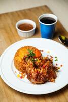 Hähnchen Majus Biryani Reis pulao serviert im Teller mit Soße, kalt trinken, Löffel und Gabel isoliert auf hölzern Tafel Seite Aussicht von Arabisch Essen foto