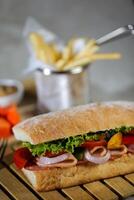 Ciabatta geräuchert Schinken Sandwich isoliert auf hölzern mit Mayonnaise tauchen und Französisch Fritten Eimer Tafel Seite Aussicht von Italienisch schnell Essen auf grau Hintergrund foto