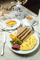 ausgestopft Omelette mit bown brot, Fleisch, Gemüse Salat umfassen Tomate, Kartoffel, Grüner Salat Blatt und Karotte mit Tee, Kaffee, und Süss Melone serviert auf Essen Tabelle oben Aussicht gesund Frühstück foto