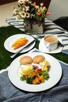 Ei Benedikt Schieberegler mit Gemüse Salat umfassen Tomate, Kartoffel, Grüner Salat Blatt und Karotte mit Tee, Kaffee, und Süss Melone serviert auf Essen Tabelle oben Aussicht gesund Englisch Frühstück foto