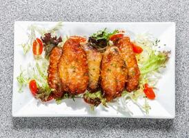 Knoblauch Honig Hähnchen Flügel mit Tomate und Kohl Salat serviert im Gericht isoliert auf Hintergrund oben Aussicht von Hong kong Essen foto