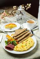 ausgestopft Omelette mit bown brot, Fleisch, Gemüse Salat umfassen Tomate, Kartoffel, Grüner Salat Blatt und Karotte mit Tee, Kaffee, und Süss Melone serviert auf Essen Tabelle oben Aussicht gesund Frühstück foto