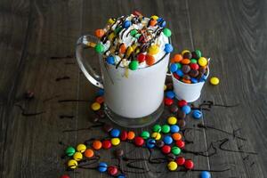 streuen Eis Sahne Shake mit bunt Süßigkeiten serviert im Glas isoliert auf Tabelle Seite Aussicht von gesund trinken foto