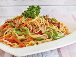 Hähnchen Chinesisch Nudeln umfassen Brokkoli, Karotte, Tomate und Frühling Zwiebel serviert im Gericht isoliert auf Tabelle Nahansicht Seite Aussicht von Chinesisch Essen foto