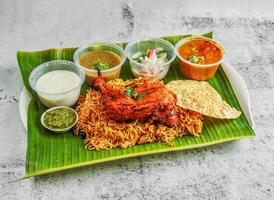 Tandoori Hähnchen Briyani mit Salat, Chutney, Raita und Soße serviert im Gericht isoliert auf Banane Blatt oben Aussicht von indisch und Singapur würzig Essen foto