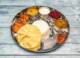 Süd indisch Vegetarier Mahlzeit Thali Gemüse, Curry, Reis, Raita, Korma, kesari halwa und Chapati serviert im Gericht isoliert auf hölzern Tabelle oben Aussicht von indisch würzig Essen foto