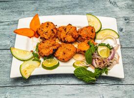 Grill Hähnchen Tikka Kabab boti mit Zitrone und Zwiebel serviert im Gericht isoliert auf hölzern Tabelle oben Aussicht von indisch würzig Essen foto