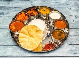 Süd indisch Fisch Mahlzeit Thali Tikka Masala, Curry, Reis, Raita, Korma, kesari halwa und Chapati serviert im Gericht isoliert auf hölzern Tabelle oben Aussicht von indisch würzig Essen foto