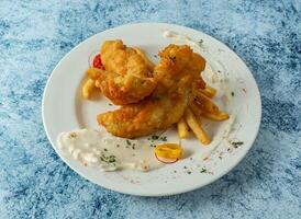 angeschlagen Fisch mit Französisch Fritten, Zitrone und tauchen serviert im Teller isoliert auf Hintergrund oben Aussicht von Italienisch Essen foto