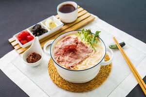 Angus Rindfleisch Fisch Udon im Reich Fisch Suppe serviert im Schüssel isoliert auf Serviette Seite Aussicht von japanisch Essen auf Tabelle foto