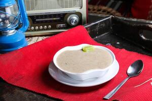 heiß Hähnchen Sahne Suppe mit Löffel serviert im Gericht isoliert auf rot Matte oben Aussicht auf Tabelle Arabisch Essen foto