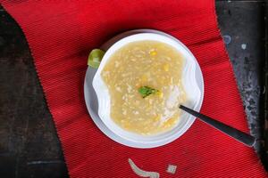 heiß Hähnchen Mais Suppe mit Löffel serviert im Gericht isoliert auf rot Matte oben Aussicht auf Tabelle Arabisch Essen foto