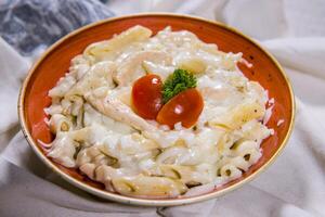 Hähnchen Pasta im Weiß Soße mit Tomate serviert im Gericht isoliert auf Essen Tabelle oben Aussicht von Mitte Osten Gewürze foto